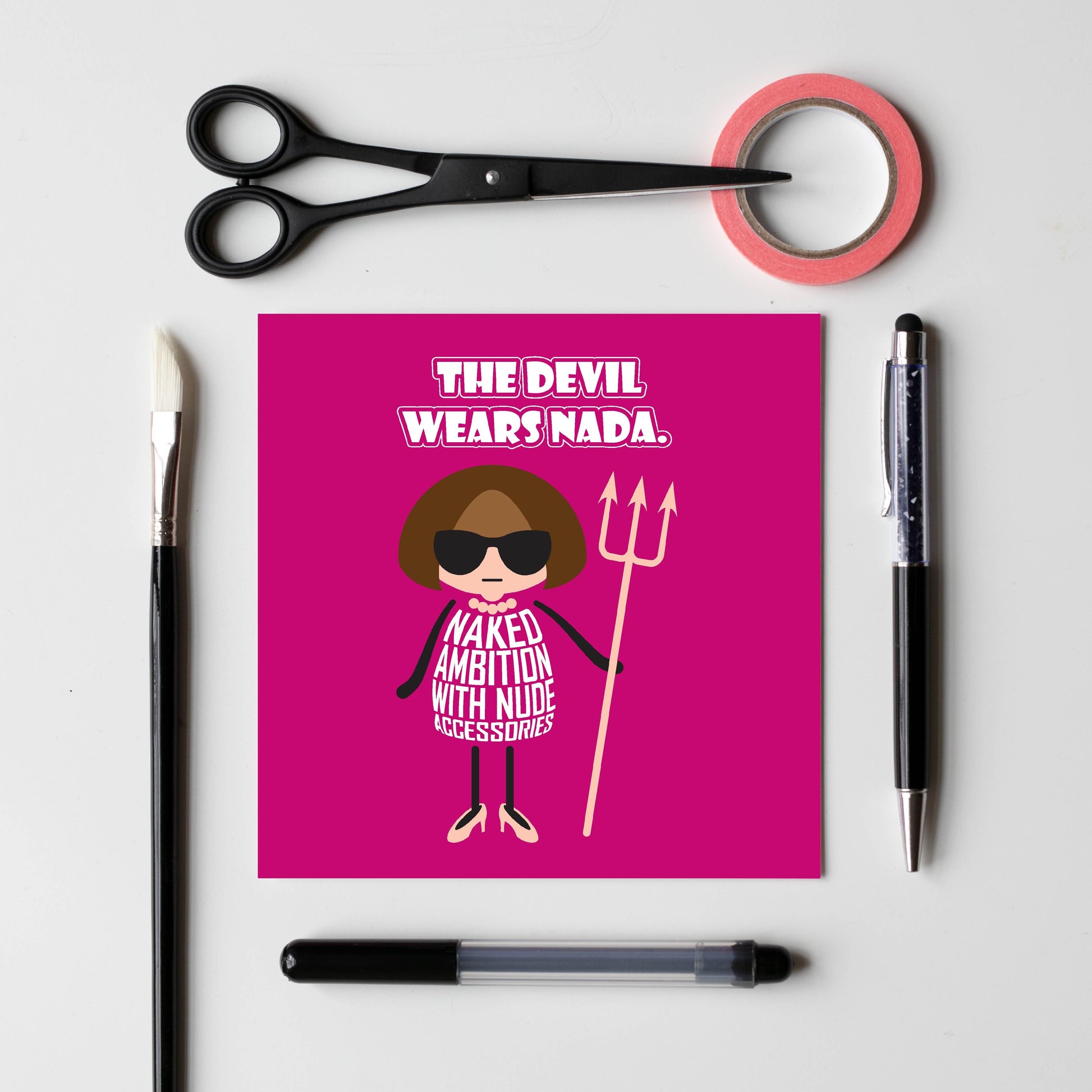 Card titled “Devil wears Nada” in white text on a pink background. A cartoon Anna Wintour wears a nude-coloured necklace, nude shoes and a nude Devil trident.  Her dress is made of text which states “Naked ambition with nude accessories” 