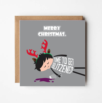 Card titled Merry Christmas. Cartoon man is lying on ground asleep – obviously drunk – next to a spilled glass of red wine and wearing a pair of novelty reindeer antlers.  His t-shirt says Time to get Blitzened. Card is 150mm square with eco-Kraft envelope.