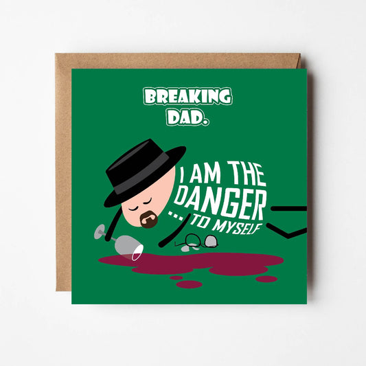 Card titled Breaking Dad. Cartoon of Walter White lies on ground asleep. He wears his pork pie hat but his broken glasses lie to one side along with a spilled drink. Walter’s body is made of text which says “I am the danger… to myself”. Card is 150mm square with eco-Kraft envelope.