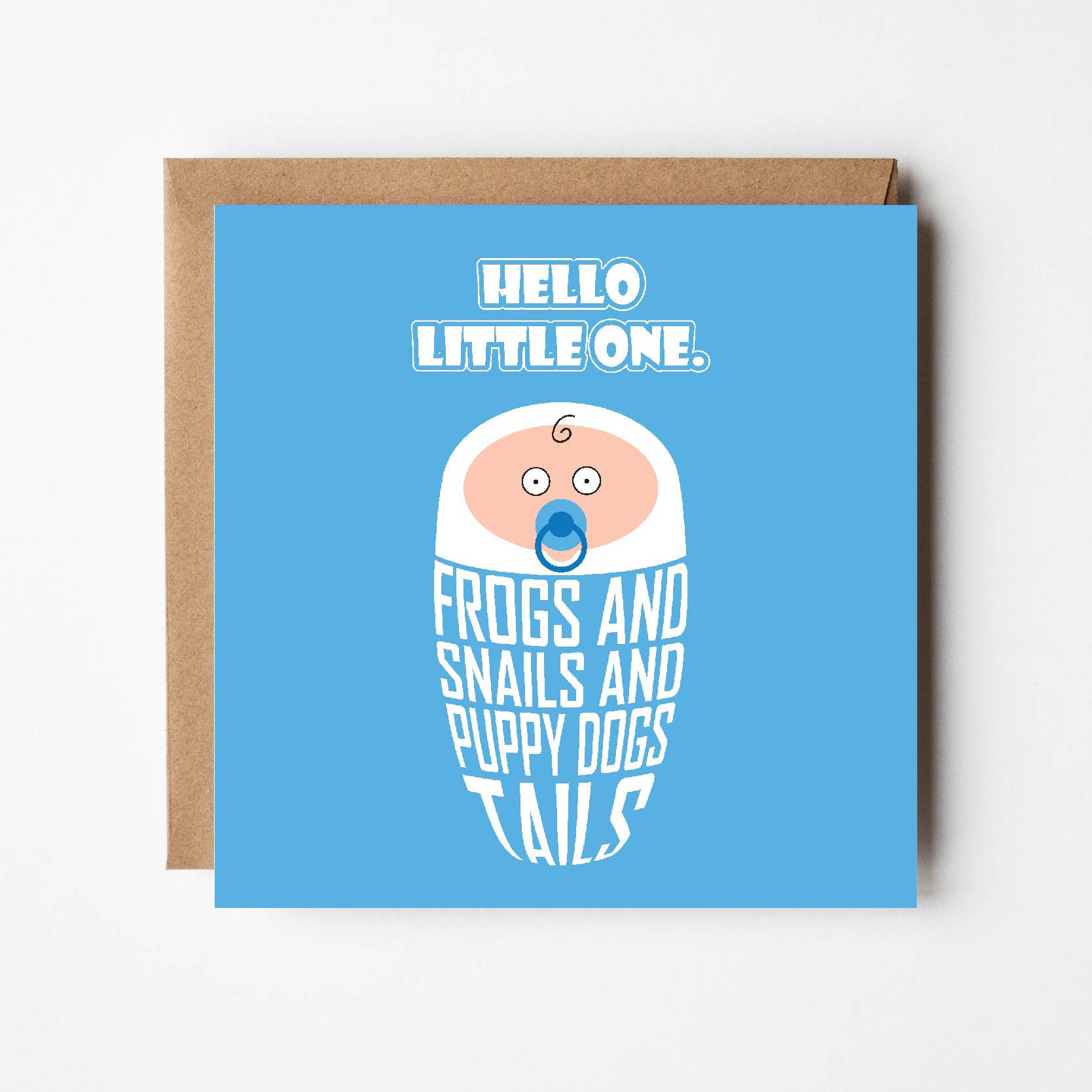 Card titled Hello Little One in white text on blue background.  Cartoon baby is swaddled in lettering which reads “Frogs and snails and puppy dog tails.”  Card is 150mm square and supplied with eco-Kraft envelope.  