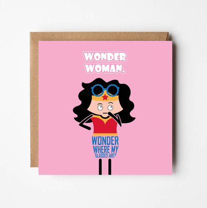 Card titled Wonder Woman in white text on pink background.  A cartoon Wonder Woman stands with her glasses up on her head and queries: Wonder where my glasses are?  Card is 150mm square and supplied with eco-Kraft envelope.